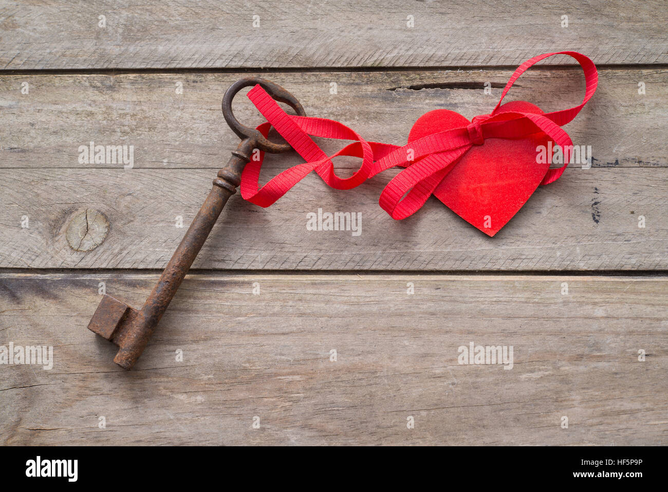 key tied to a red heart with a red ribbon. Wooden background Stock ...