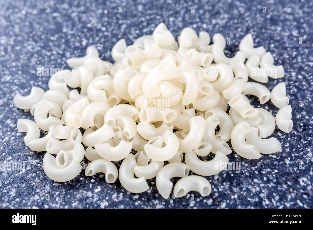 White rice elbow macaroni on a mottled grey blue background Stock Photo