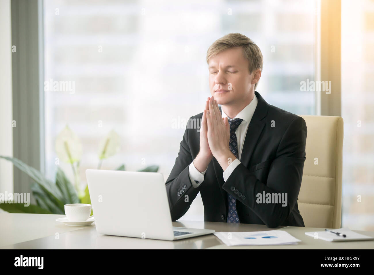 Businessman in yoga pose at the office desk Stock Photo - Alamy