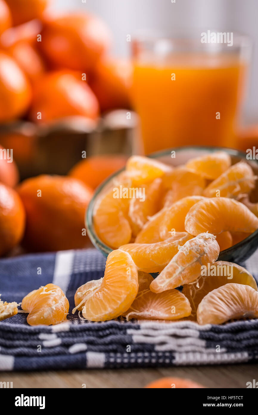 Tangerines, peeled tangerine and tangerine slices on a blue cloth. Mandarine juice. Stock Photo