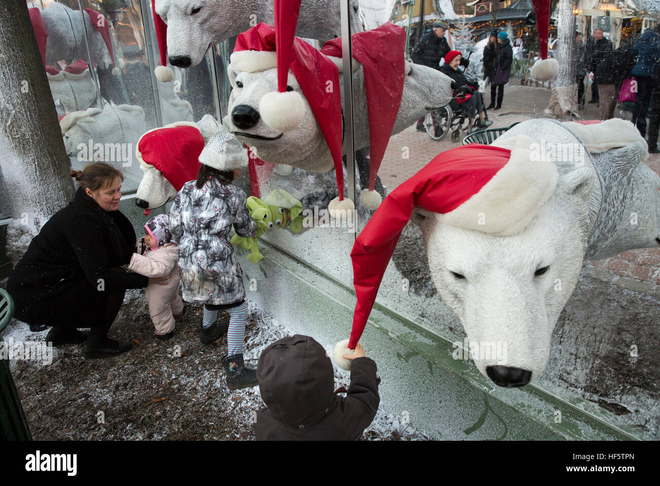 Denmark, Copenhagen, Tivoli Gardens at Christmas, children playing by polar bear heads wearing christmas hats Stock Photo