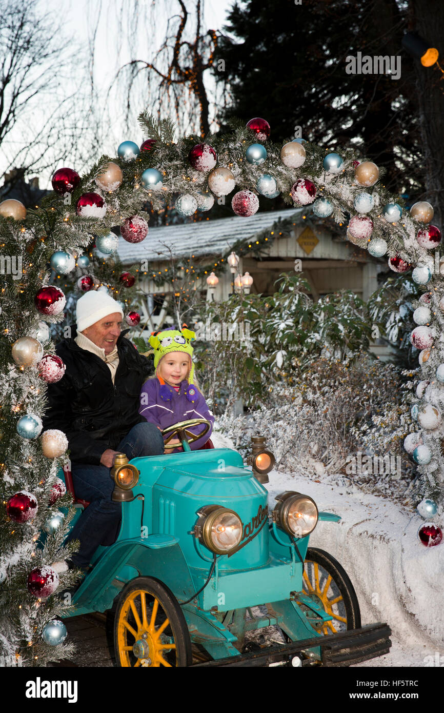 Denmark, Copenhagen, Tivoli Gardens, Christmas, child with grandfather on children’s ride at dusk Stock Photo