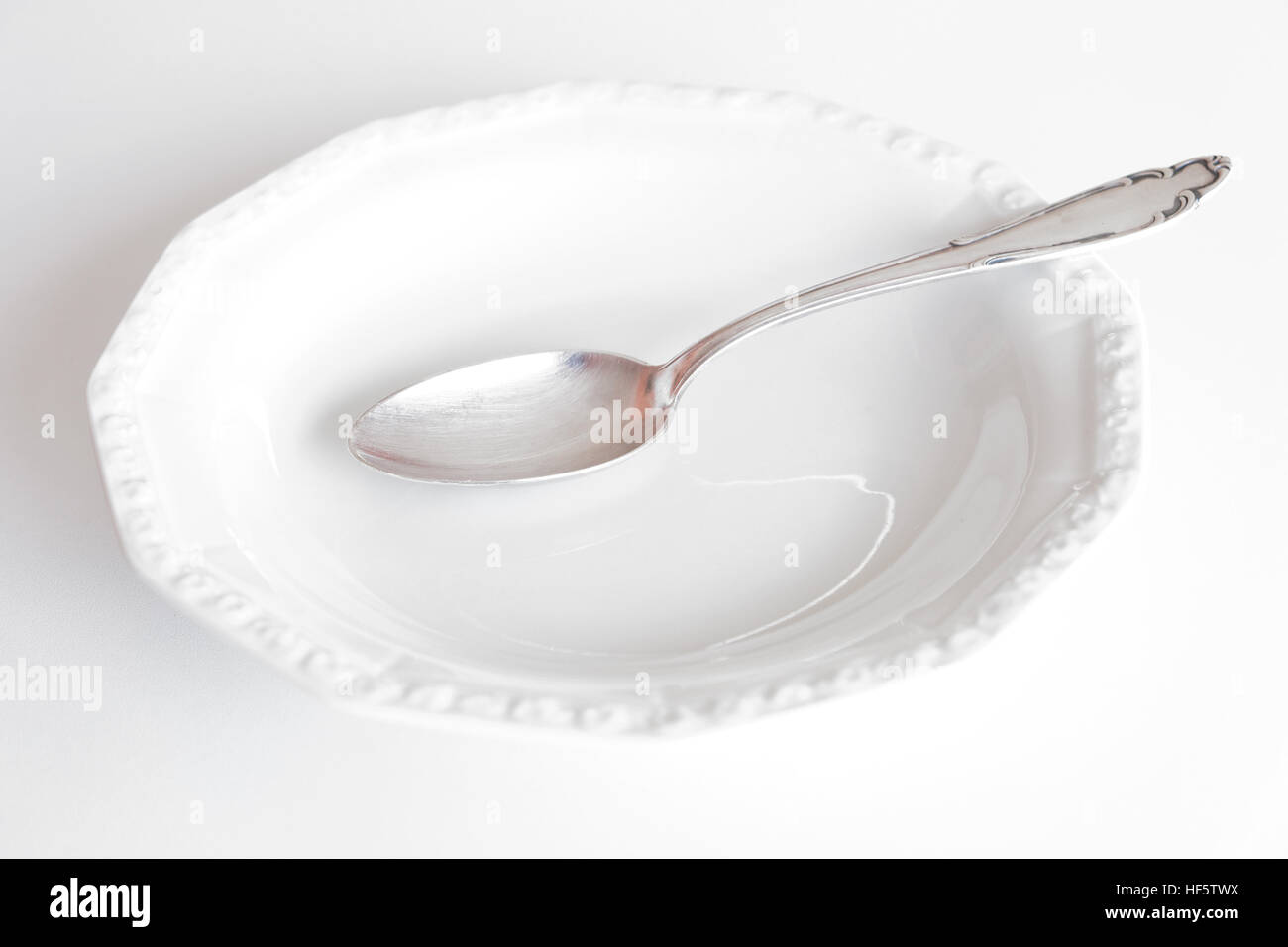 empty plate with silver spoon isolated on white background Stock Photo