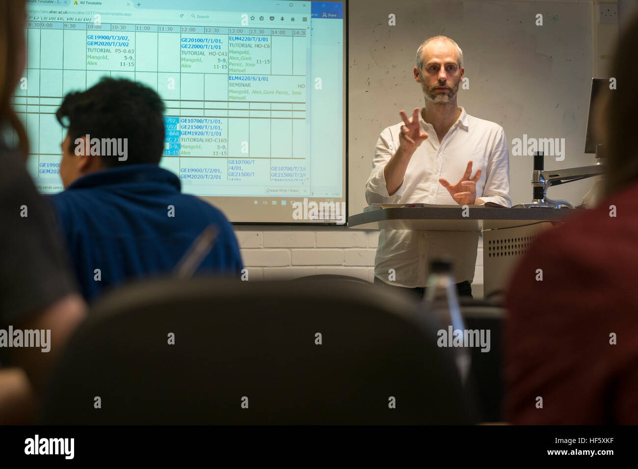 Higher Education in the UK: - a male lecturer leading a class seminar tutorial to undergraduate students in a classroom Stock Photo