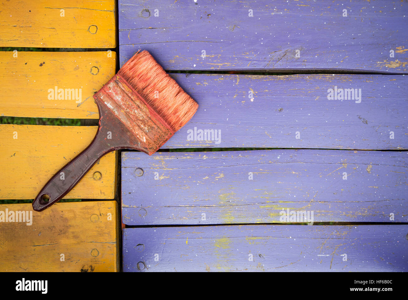 used brush with bits of dried paint on colored wood background Stock