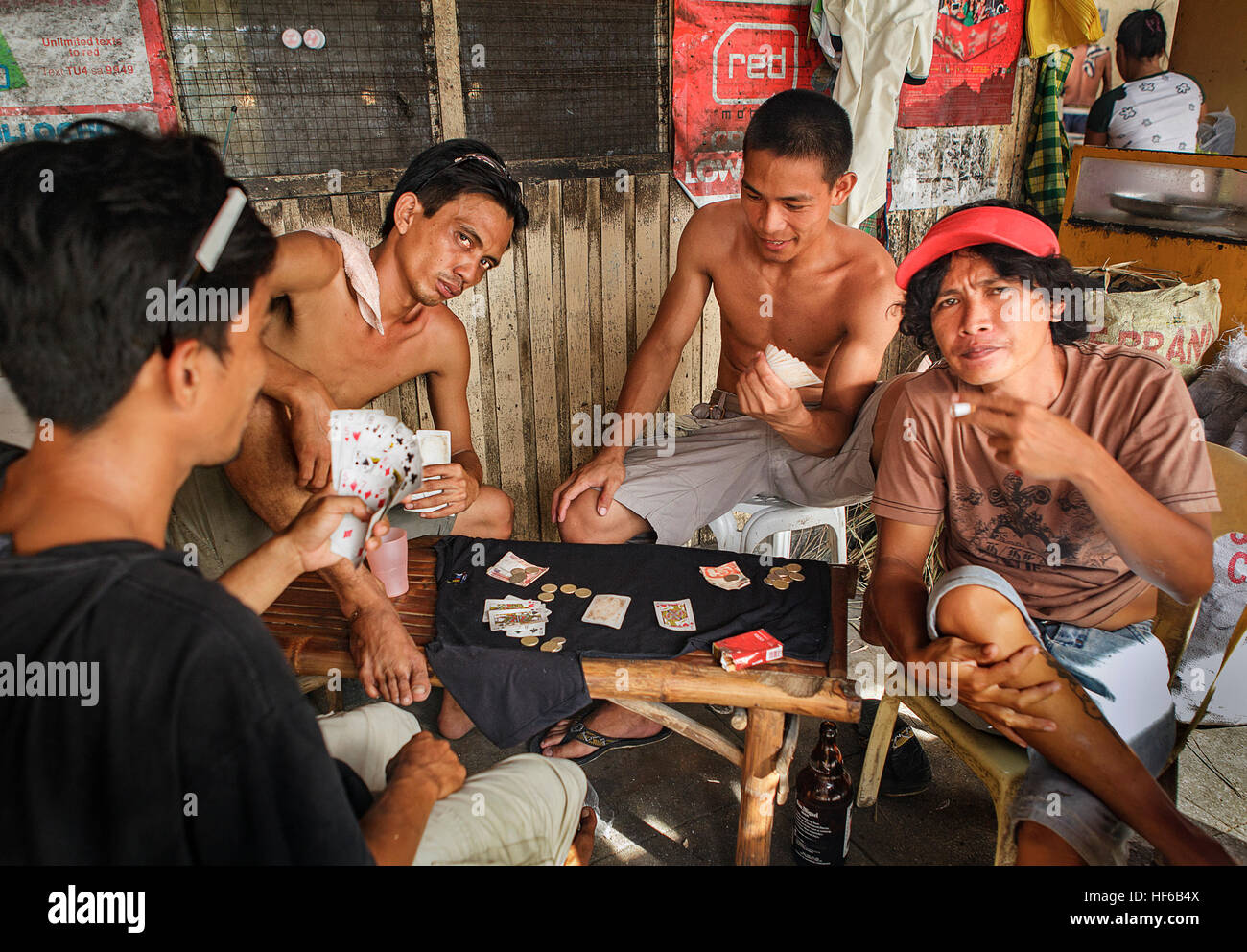 Four Filipino men play a gambling game with cards in Bogo City, Cebu Island, Philippines. Stock Photo