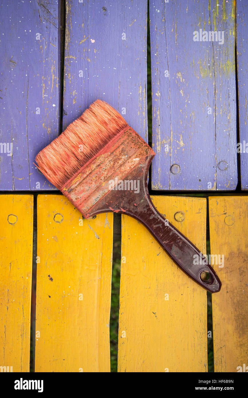 used brush with bits of dried paint on colored wood background Stock