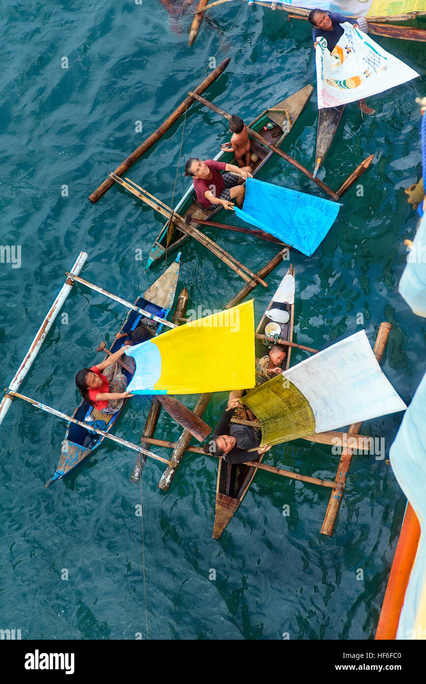 Destitute families with makeshift catch nets beg from passenger ferries in Cebu Harbor, Philippines. Stock Photo