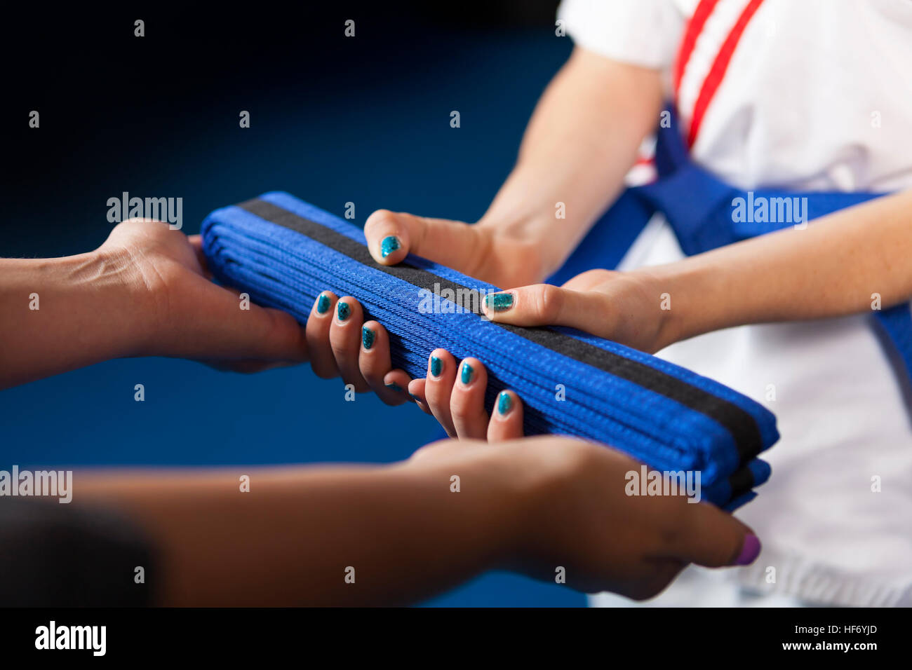 Karate Belt Promotion. Teacher handing belt to youth student. Shallow Depth of Field, focus is on the belt. Stock Photo