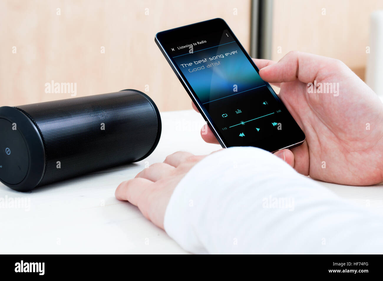 Playing music on a wireless speaker. Stock Photo