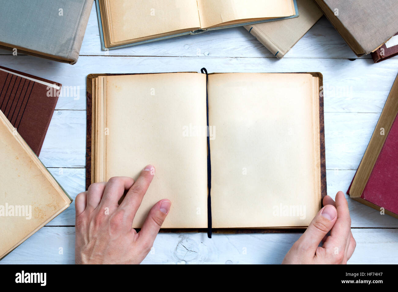 Old books with empty pages for your text and man's hand shows important place. Stock Photo