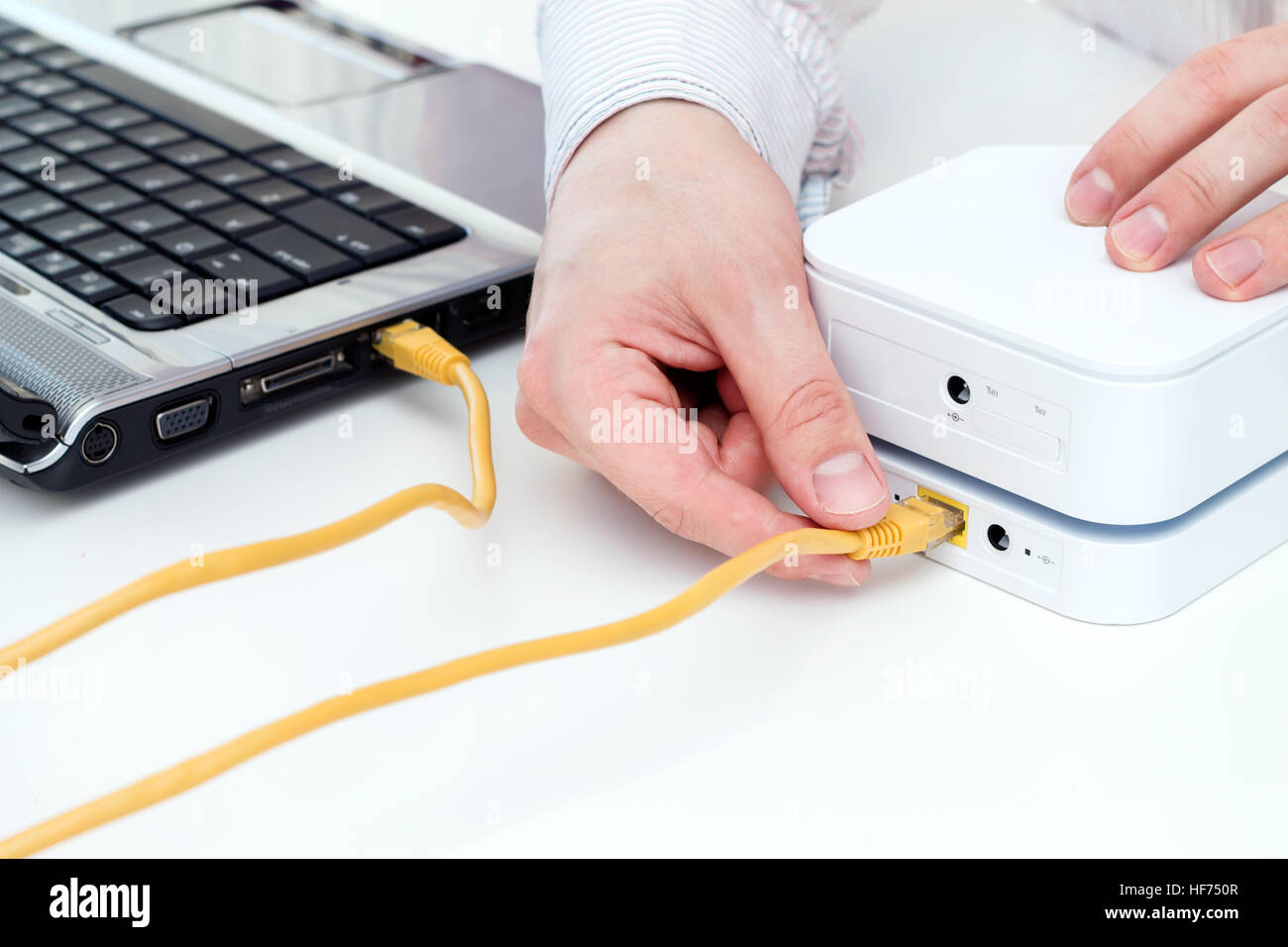 Businessman connects his laptop to the mobile WiFi router with LAN cable.  Focus on router Stock Photo - Alamy