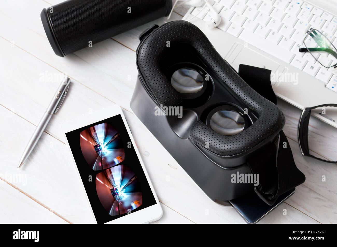 VR ocular and smartphone with VR car game lying on white wooden desk ...