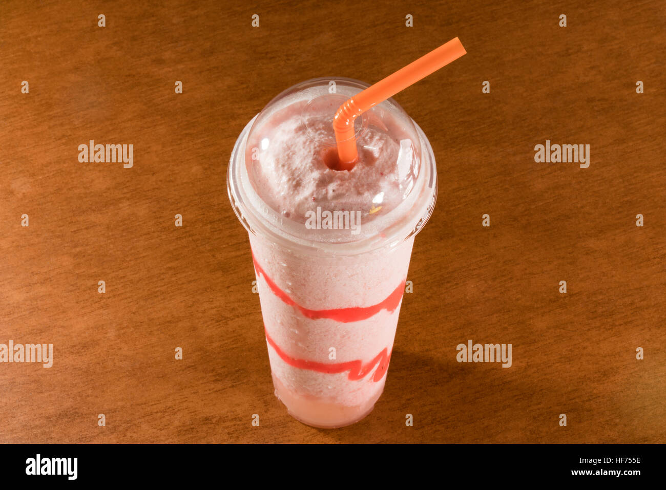 Fresh strawberry smoothie in plastic cup on ceramic floor tile Stock Photo