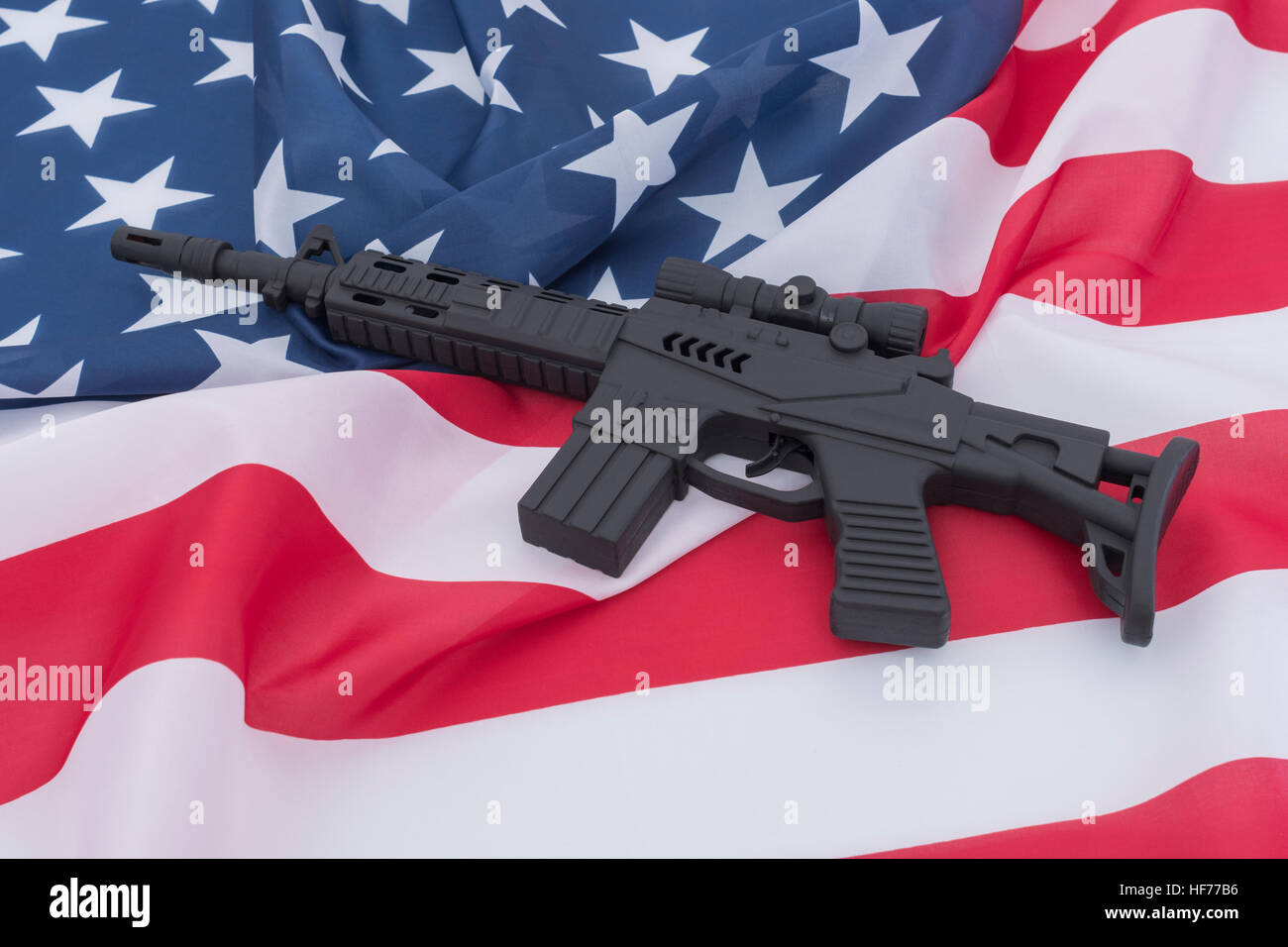 Black toy assault rifle set against US / American flag / Stars & Stripes. For US gun violence crime, US gun law, terrorism, Chicago crime, arsenal Stock Photo