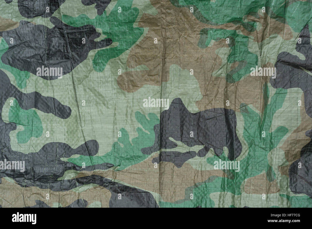 Section of green camouflage ground sheet material, which can also be used to build a survival shelter / emergency shelter against the elements. Stock Photo