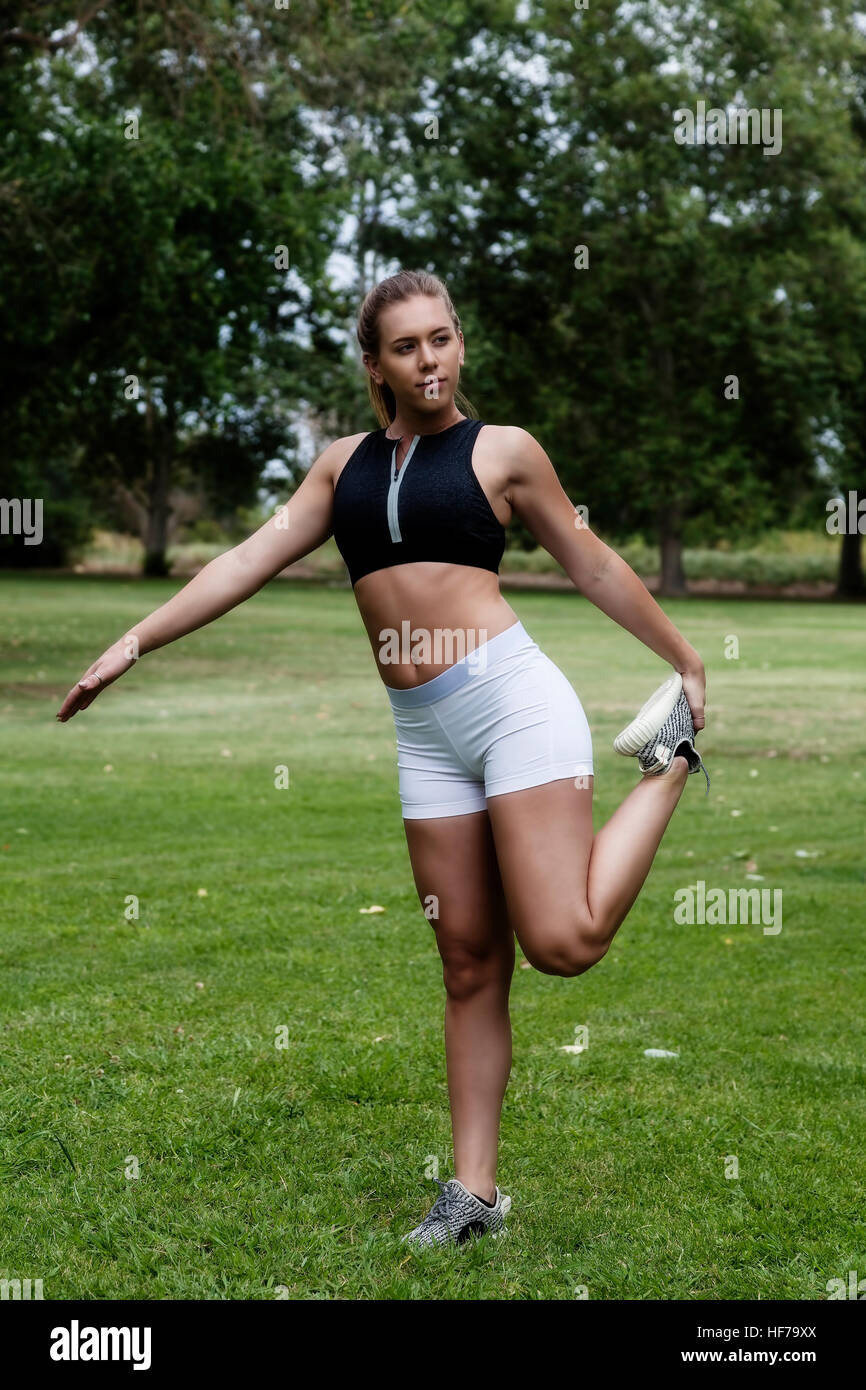 Caucasian Teen Girl Pulling On Foot To Stretch Leg In Park White Shorts  Black Top Stock Photo - Alamy