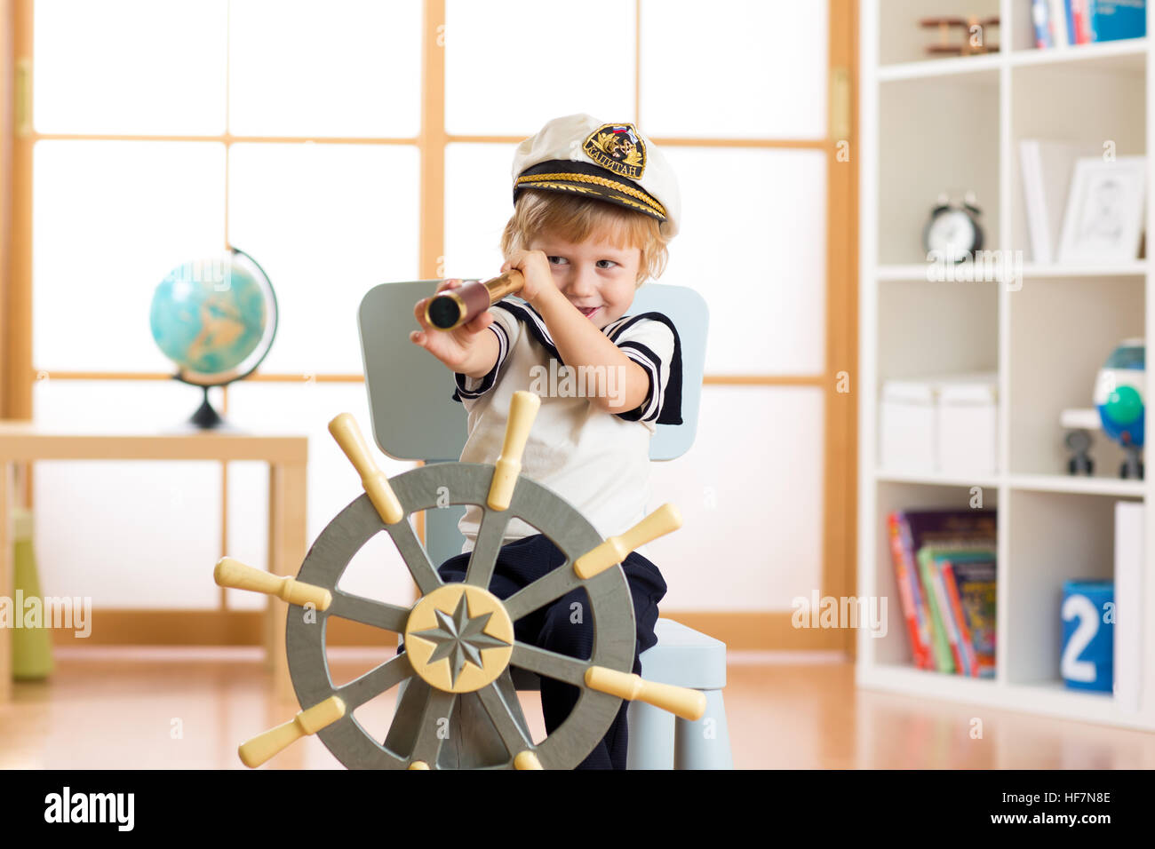 Child pretend to be sailor. Kid boy looking through spy glass playing at home. Stock Photo