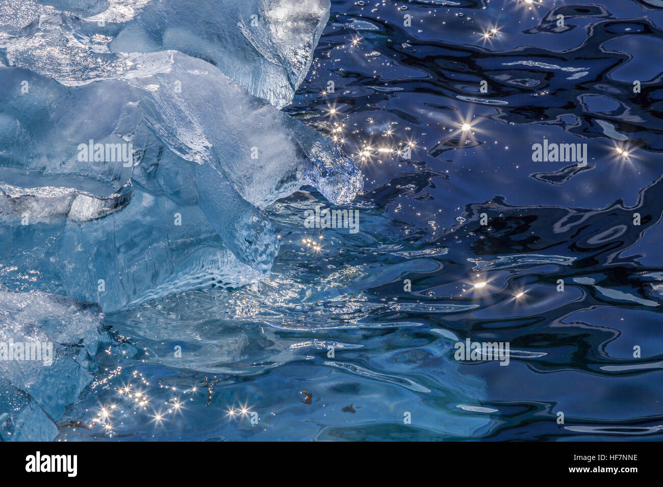 Pieces of Iceberg drifting at the shore and sun beams shining on the water surface, Greenland Stock Photo