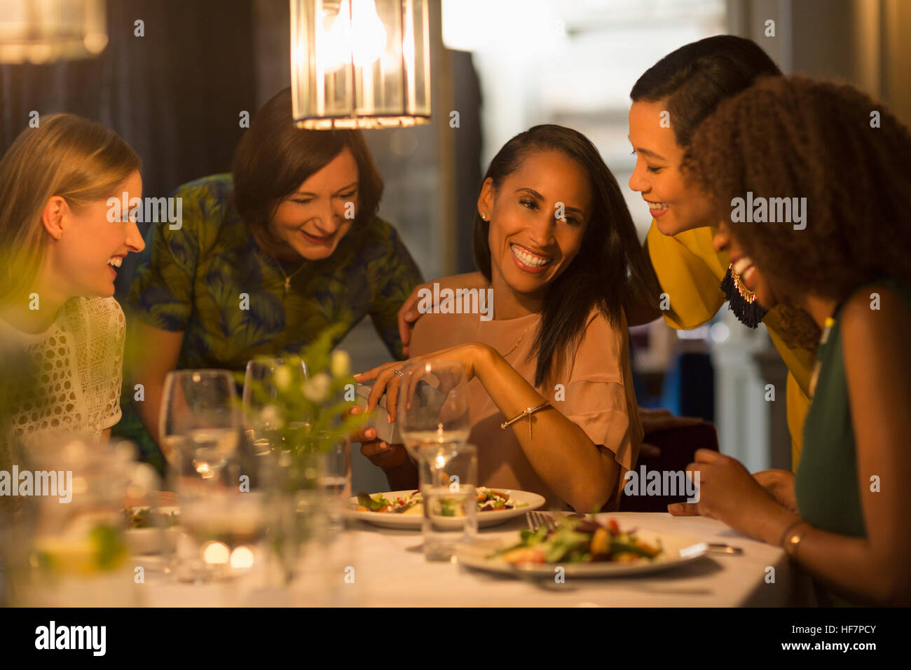 Smiling friends celebrating woman’s birthday at restaurant table Stock Photo