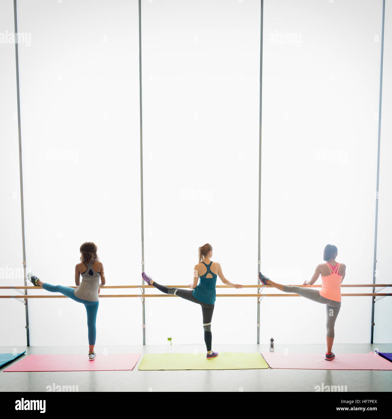 Women stretching legs at barre in exercise class gym studio Stock Photo