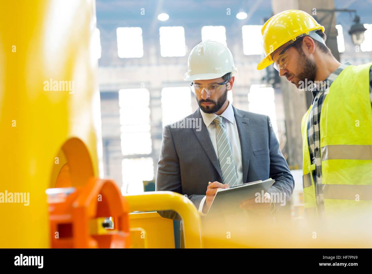 Manager and steel worker examining equipment in factory Stock Photo