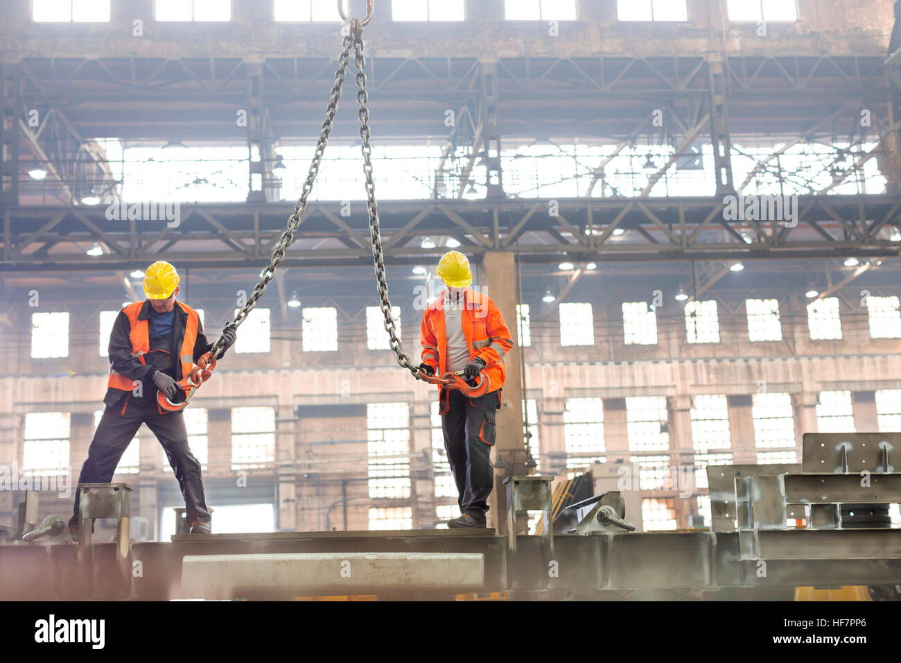 Steel workers with crane hooks in factory Stock Photo