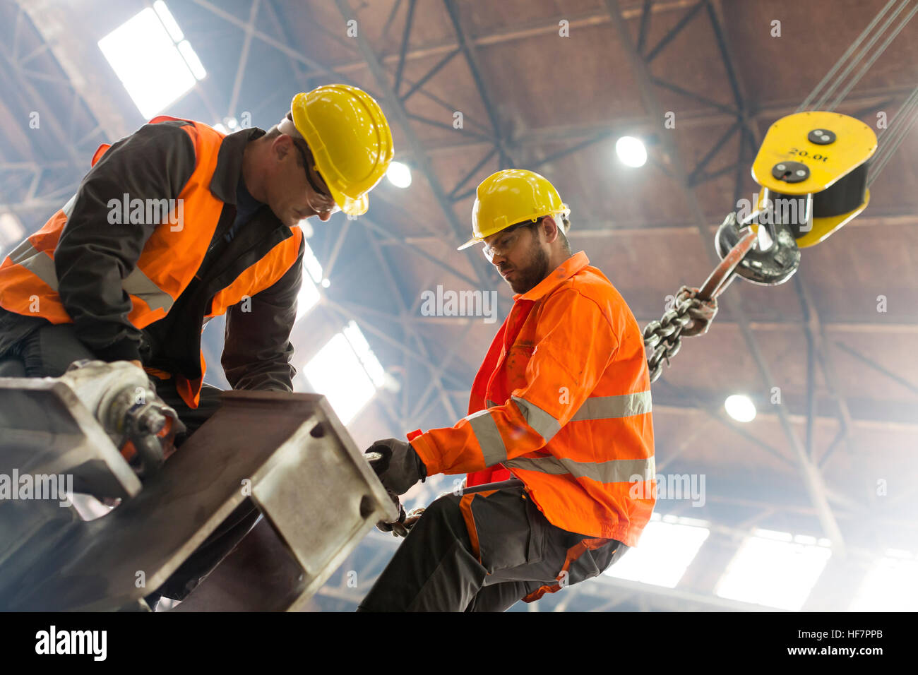 Steel workers fastening crane hook to steel in factory Stock Photo