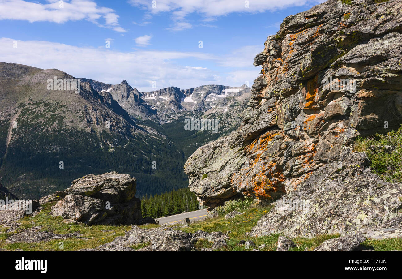 The Rocky Mountains with large lichen covered boulders and glimpse of state highway 34 on a bright summer day. Stock Photo