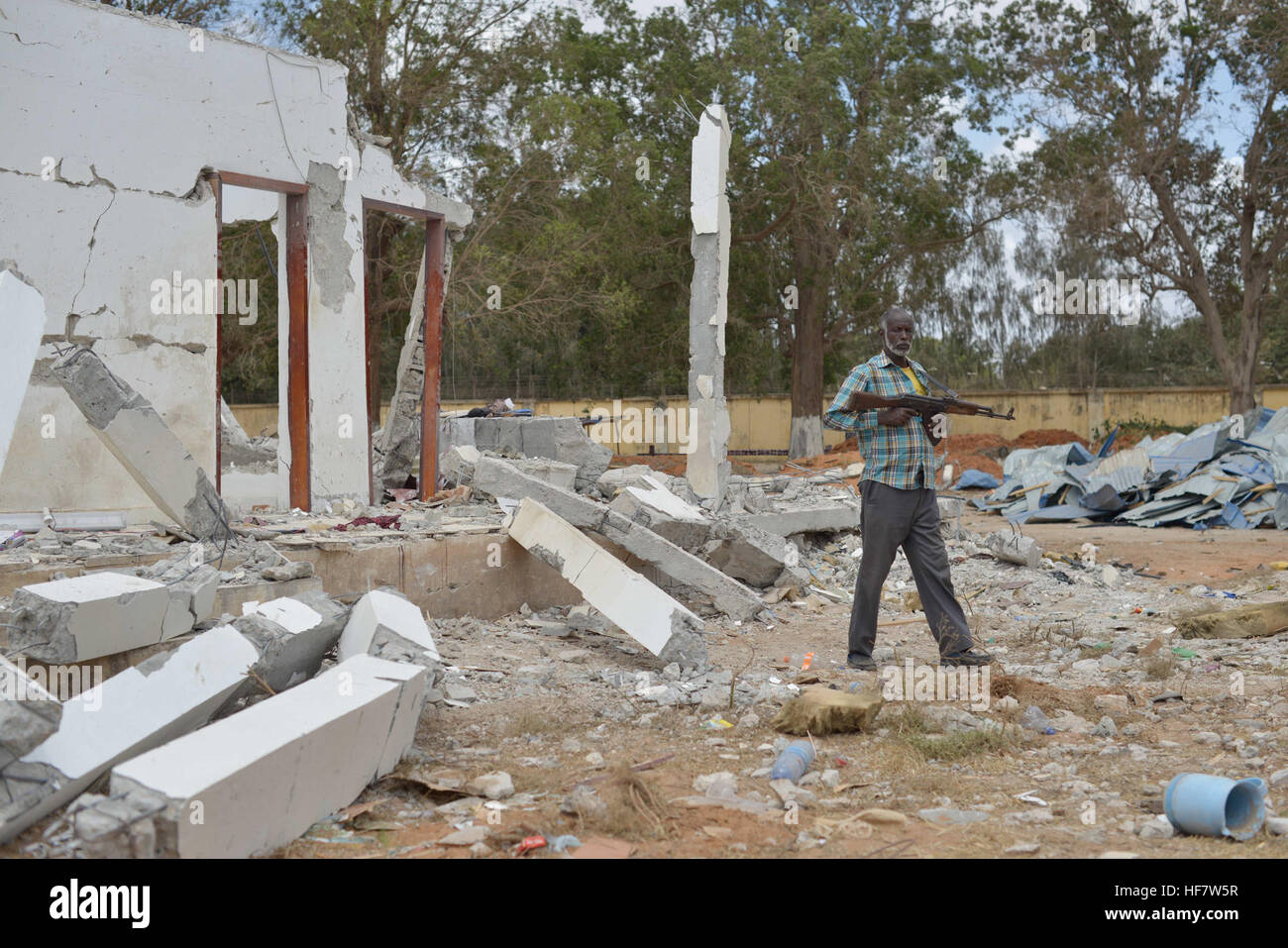 A member of the Somali Police Force surveys a building in Afgoye, Somalia, on October 25, 2016, that was damaged by a bomb blast at a police station the previous week. The attack is part of ongoing security challenges in the region. Stock Photo