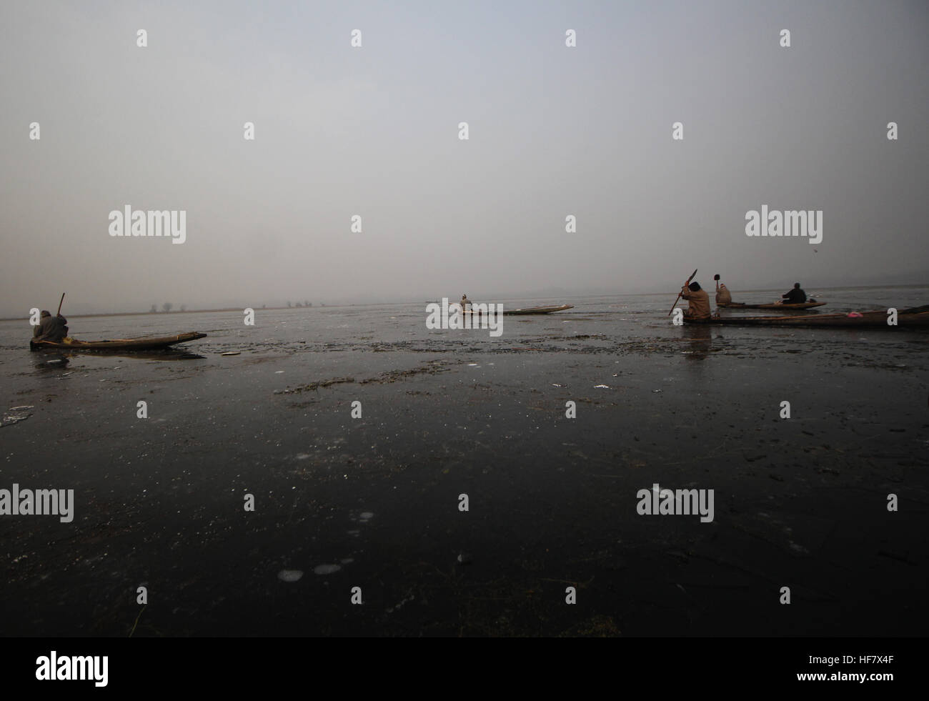 Srinagar, India. 27th Dec, 2016. Kashmiri boatmen trying to make way for his boat amid the frozen waters of the lake in Indian Administered Kashmir. The Himalayan region witnessed sudden drop in temperatures after a decade with experts sounding caution over such drastic climate change. © Umer Asif/Pacific Press/Alamy Live News Stock Photo