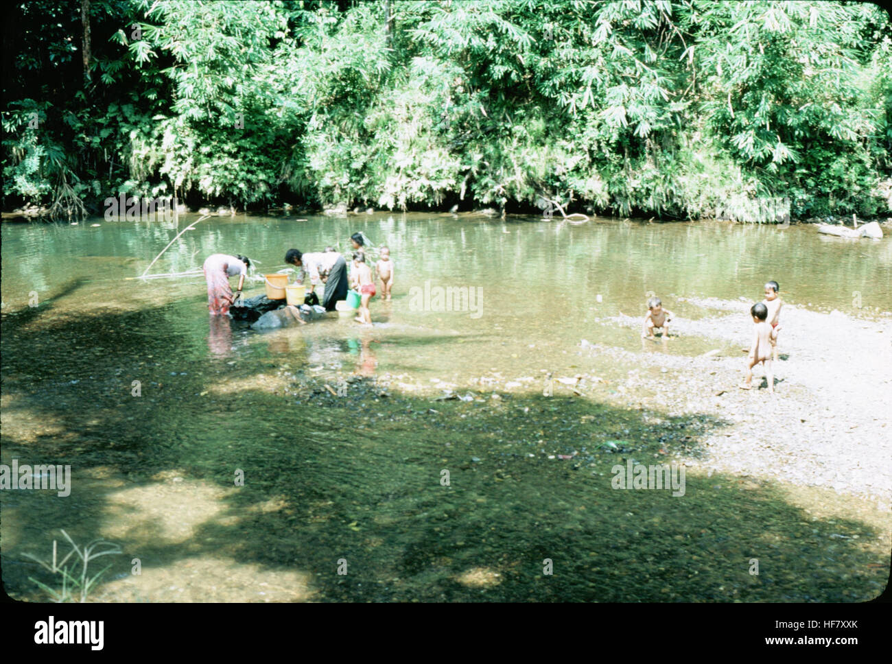 Dayak people washing and bathing in the river near their longhouses; Kuching area, Sarawak, Malaysia.  People seemed to be happy, though shy. Stock Photo