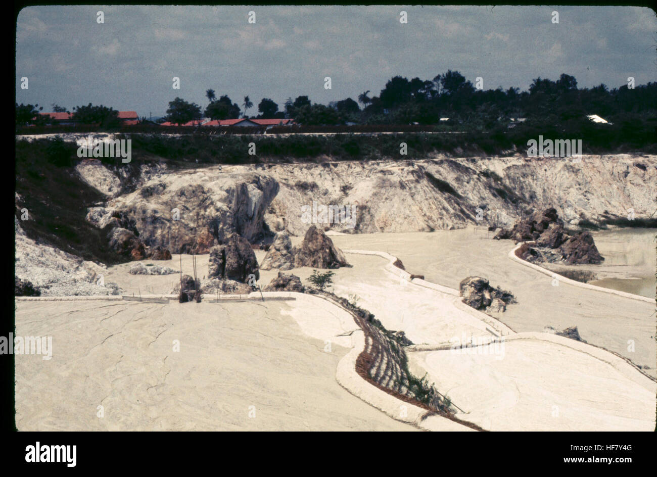This image shows an open-pit mining operation for tin located outside Kuala Lumpur, Malaysia. The method involves removing earth to access the tin ore beneath, a significant mining process in the region. Stock Photo