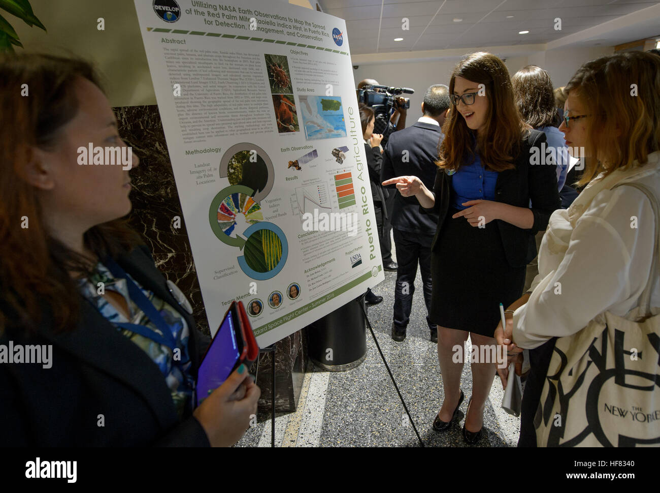 CUNY Hunter college Master's graduate Julia Marrs, center, talks to attendees about her work with Puerto Rico agriculture during the 2016 Annual Earth Science Applications Showcase, Wednesday, Aug. 10, 2016, at NASA Headquarters in Washington. Every summer students and young professionals from NASA’s Applied Sciences’ DEVELOP National Program come to NASA Headquarters and present their research projects. DEVELOP is a training and development program where students work on Earth science research projects, mentored by science advisers from NASA and partner agencies, and extend research results t Stock Photo