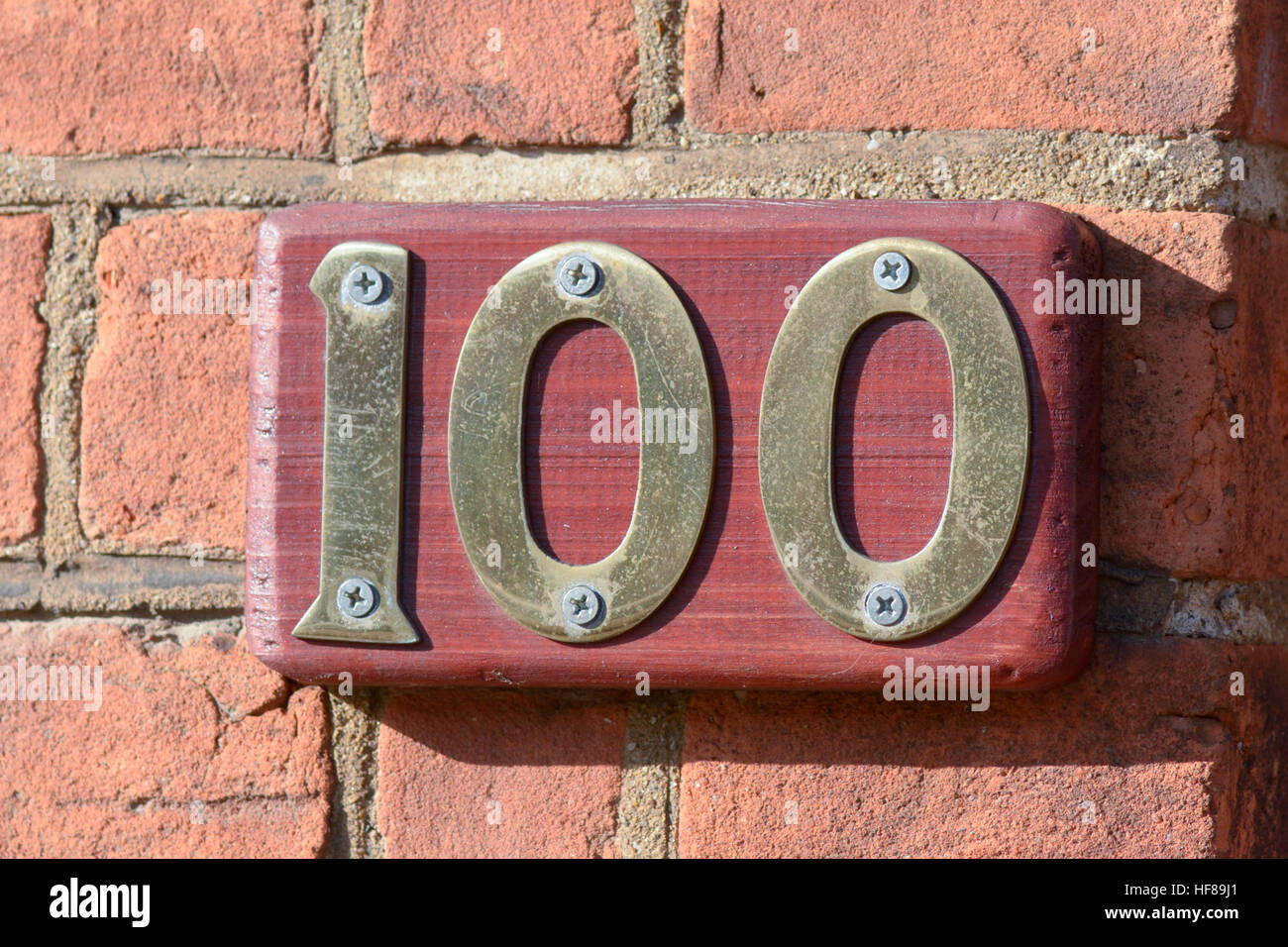 House number 100 sign on wall Stock Photo