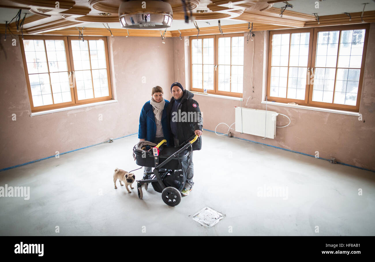 Braunsbach, Germany. 23rd Dec, 2016. Thomas Philipp-Hopf, operator of the guesthouse 'Zum Loewen', his wife Heike Philipp and their child and family dog stand in the main hall of the guesthouse in Braunsbach, Germany, 23 December 2016. The couple is currently reconstructing the guesthouse which was destroyed entirely during the flood. Photo: Christoph Schmidt/dpa/Alamy Live News Stock Photo