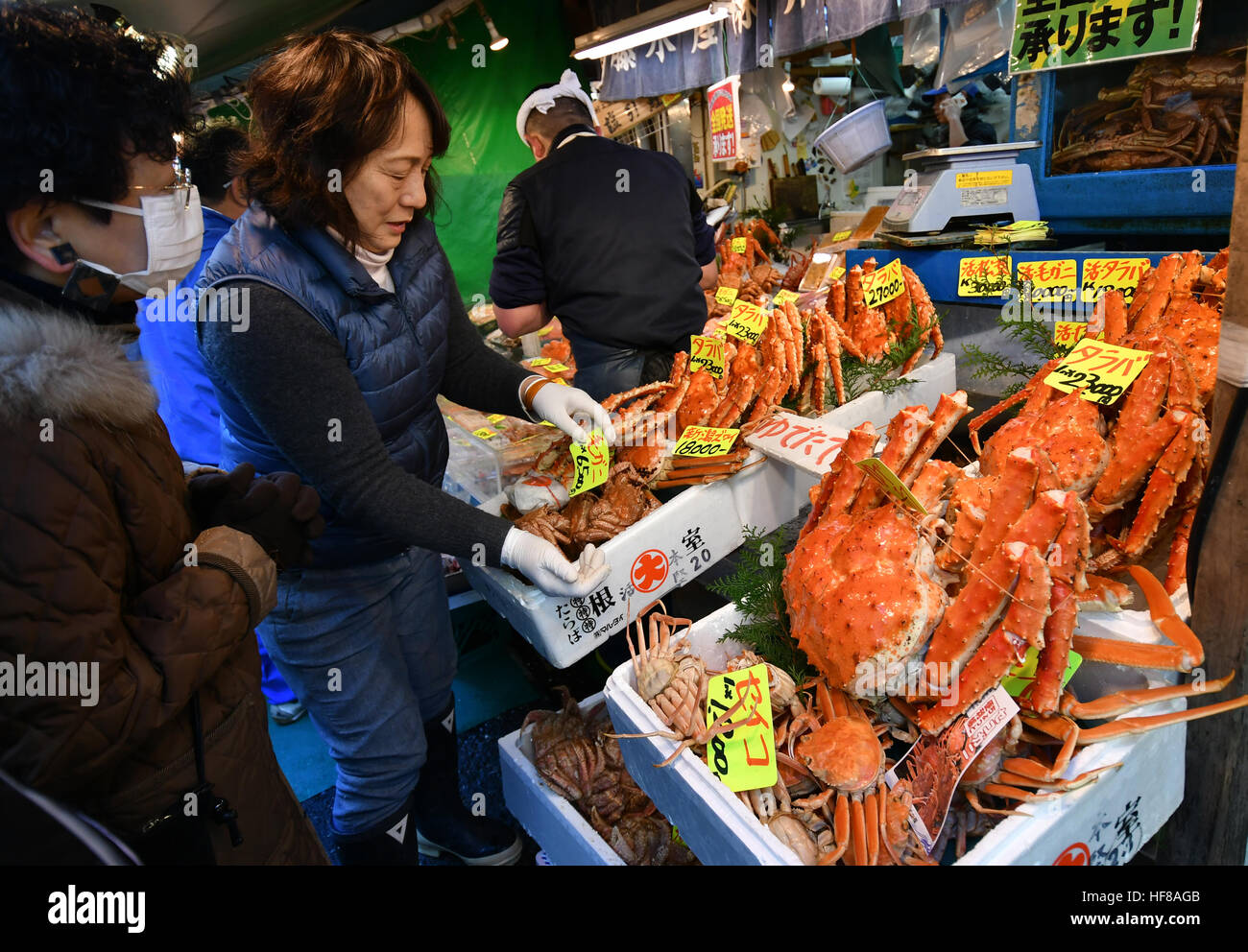 Tokyo, Japan. 28th Dec, 2016. A flock of bargain-hunters and some foreign tourists throngs the narrow maze of alleys lined with hundreds of small shops and stalls selling fresh fish and marine products outside of Tokyo's main fish market in Tsukiji on Thursday, December 28, 2016, the customary last business day of the year. The planned move of the nation's largest wholesale market to the neighboring Toyosu district still hangs in limbo over soil pollution fears and bickering between those for and against the change. © Natsuki Sakai/AFLO/Alamy Live News Stock Photo