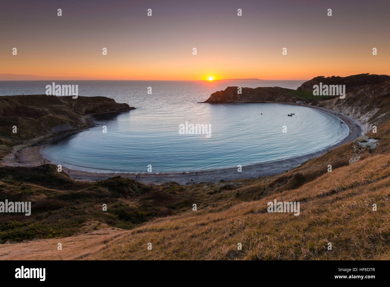 Lulworth Cove, Dorset, UK.  28th December 2016.  UK Weather.  A glorious sunset at Lulworth Cove on the Dorset Jurassic Coast looking out to sea towards the Isle of Portland. Picture: Graham Hunt/Alamy Live News Stock Photo