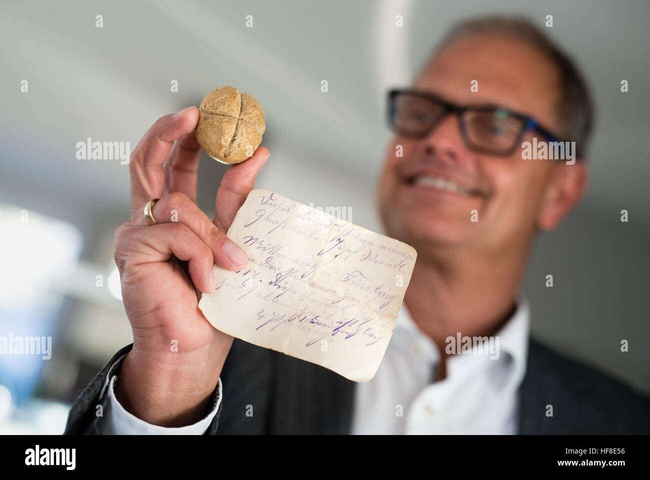 Christian Lerf hält am 14.12.2016 in seiner Wohnung in Fürstenfeldbruck (Bayern) die wohl älteste Semmel Bayerns in der Hand. Auf dem Schriftstück, das mit dem Stückcken Brot weitergereicht wurde, steht, dass die Sternsemmel von Josef Werndl in der Nähe von Tüßling kommt und damals vier Pfennig kostete. Die 1817 nahe Altötting gebackene Semmel wurde als Familienerbstück über Generationen weitergegeben. Foto: Matthias Balk/dpa (zu dpa-KORR '1817 für vier Pfennige gebacken - Bayerns älteste Semmel wird 200' vom 29.12.2016) Foto: Matthias Balk/dpa    (c) dpa - Bildfunk    Stock Photo