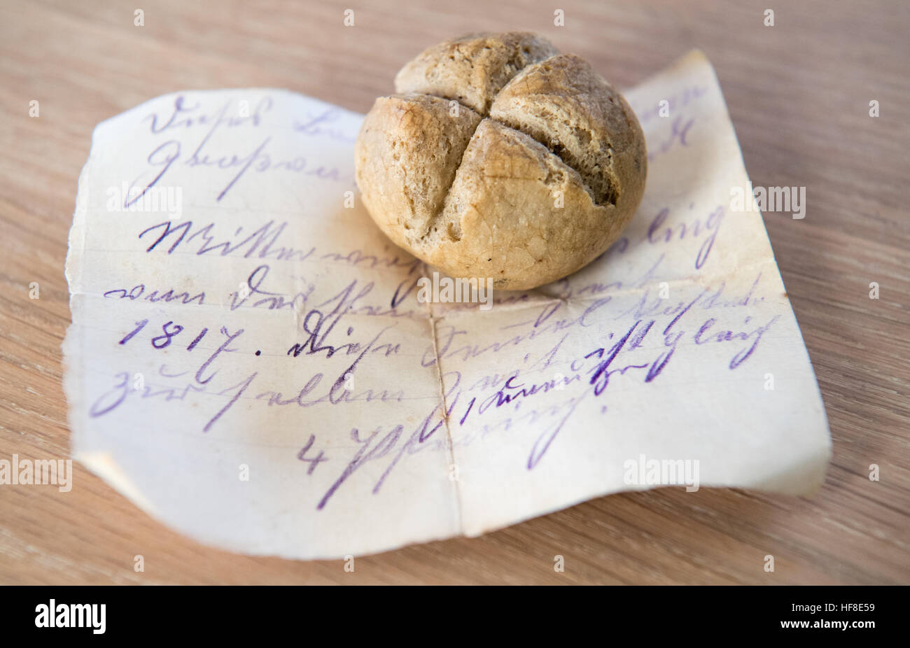 Die wohl älteste Semmel Bayerns liegt am 14.12.2016 in der Wohnung Christian Lerf in Fürstenfeldbruck (Bayern) auf einem historischen Zettel. Auf dem Schriftstück, das mit dem Stückcken Brot weitergereicht wurde, steht, dass die Sternsemmel von Josef Werndl in der Nähe von Tüßling kommt und damals vier Pfennig kostete. Die 1817 nahe Altötting gebackene Semmel wurde als Familienerbstück über Generationen weitergegeben. Foto: Matthias Balk/dpa (zu dpa-KORR '1817 für vier Pfennige gebacken - Bayerns älteste Semmel wird 200' vom 29.12.2016) Foto: Matthias Balk/dpa    (c) dpa - Bildfunk    Stock Photo