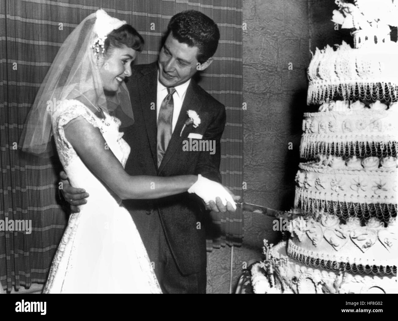 Die US-amerikanische Schauspielerin Debbie Reynolds und der Sänger Eddie Fisher schneiden am 26. September 1955 gemeinsam ihre Hochzeitstorte an. Debbie Reynolds gehörte in den 50er Jahren zu den größten 'Kassenmagneten' Hollywoods. Der Durchbruch gelang ihr 1952, als Gene Kelly sie für den Film 'Singin' in the Rain' entdeckte. | Verwendung weltweit/picture alliance Stock Photo
