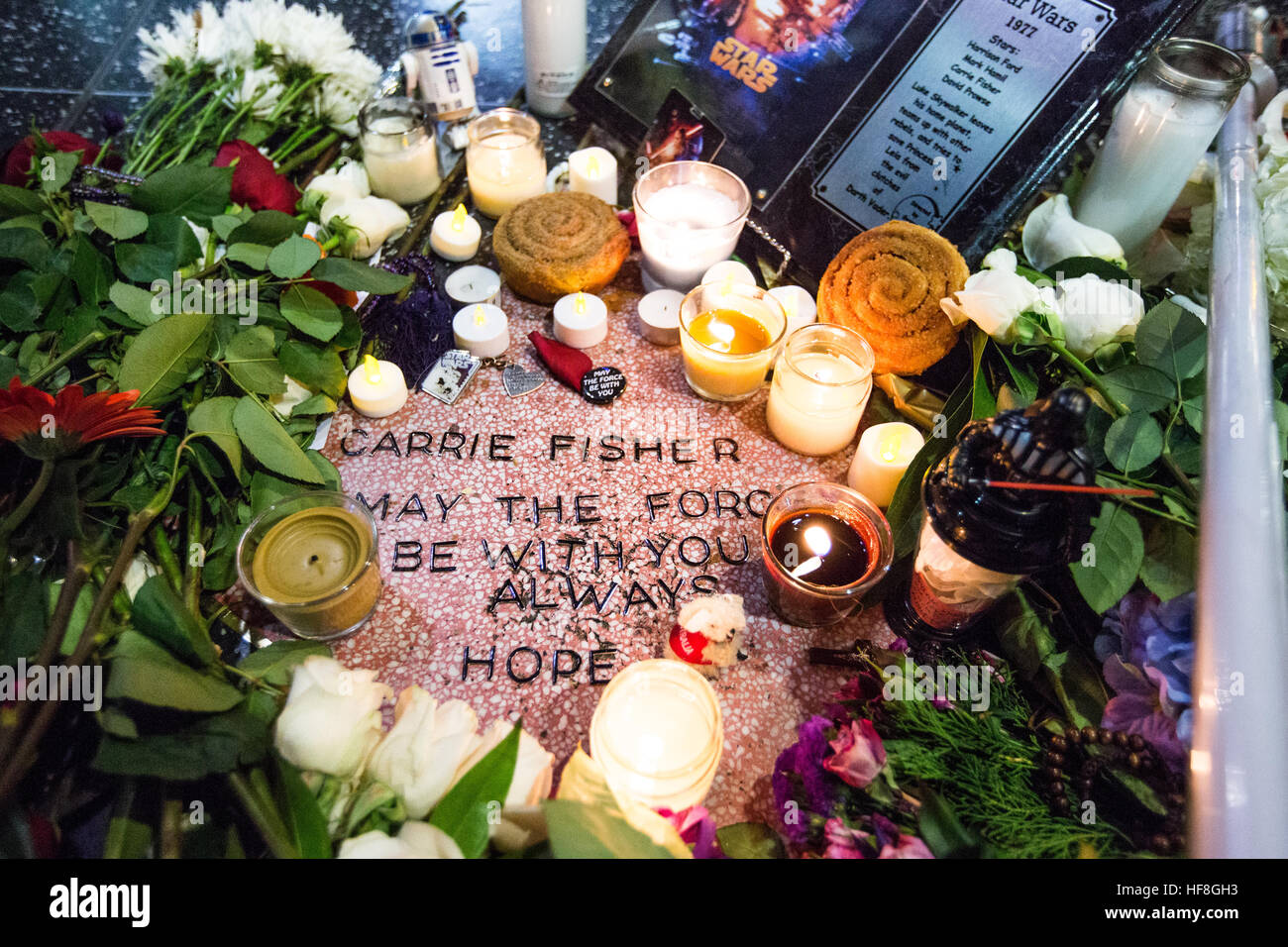 Hollywood, California, USA. 28th December, 2016. Actress Carrie Fisher, who passed away yesterday, is honored by fans with a makeshift star on the Hollywood Walk of Fame in Hollywood, California, USA.  As Carrie Fisher does not have an official star on the Hollywood Walk of Fame, her fans created one for her from a blank star near the theater where Star Wars movies have had their premieres. Along with flowers, light sabers, and momentos, there is a cinnamon bun that is symbolic of her hairdo in the role of 'Princess Leia' in the first Star Wars movie.  Credit: Sheri Determan/Alamy Live News Stock Photo