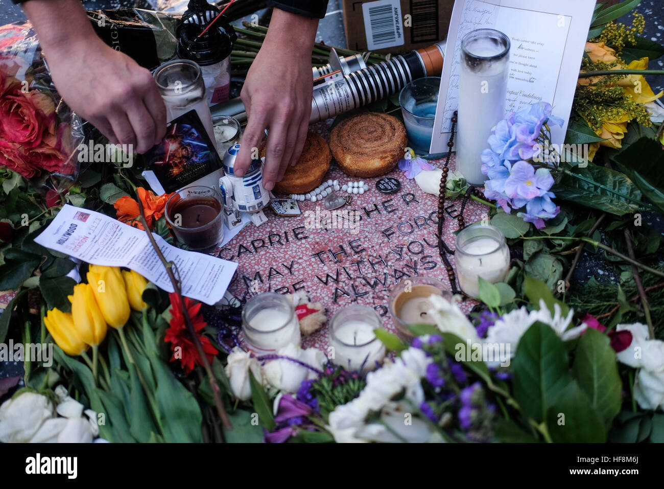 Los Angeles, USA. 29th Dec, 2016. Flowers and candles surround an impromptu memorial created on a blank Hollywood Walk of Fame star by fans of late actress and author Carrie Fisher, in Los Angeles, California, the United States, on Dec. 29, 2016. Hollywood star Debbie Reynolds died of stroke Wednesday at the age of 84, one day after her daughter Carrie Fisher's death. Carrie Fisher, the actress best known as Princess Leia in the 'Star Wars' movie franchise, died at the age of 60 on Tuesday morning, after suffering a heart attack on a flight last Friday. © Zhao Hanrong/Xinhua/Alamy Live News Stock Photo
