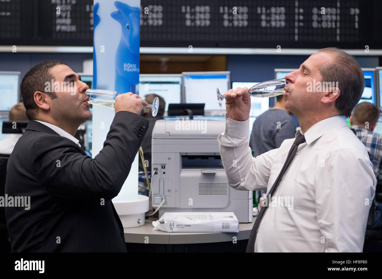 two stockbrokers drink glasses of prosecco in the trading room of stock brokers