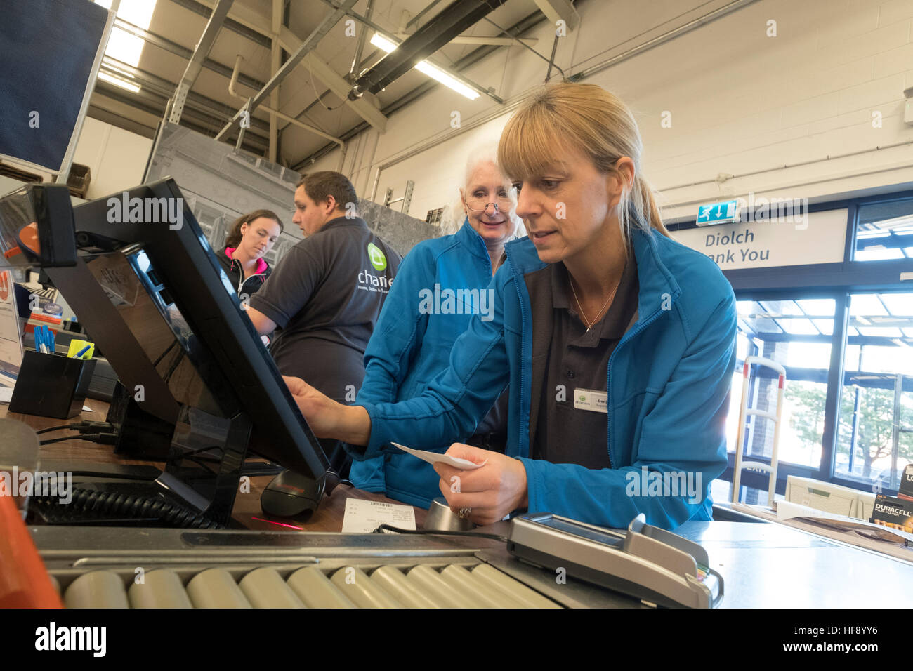A woman working a digital electronic touchscreen till on the checkout