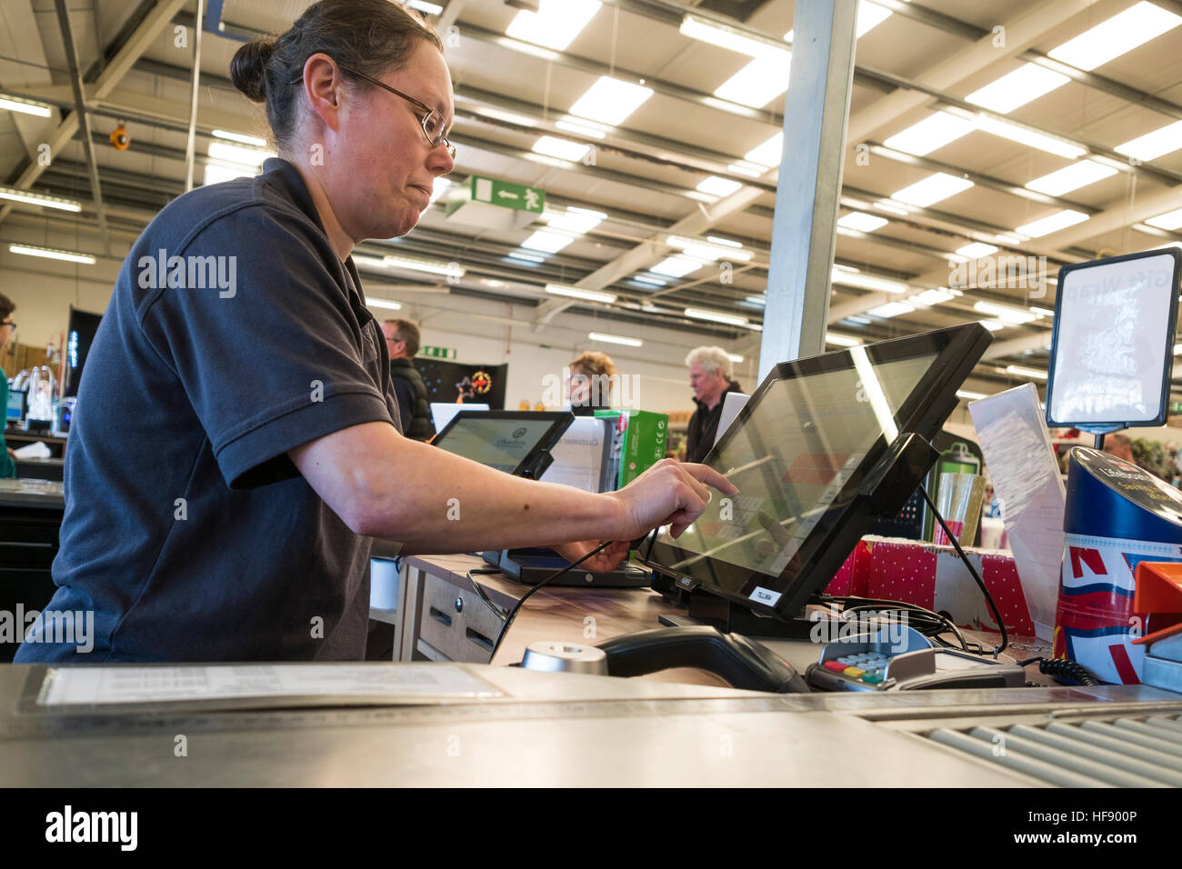 A woman working a digital electronic touchscreen till on the checkout