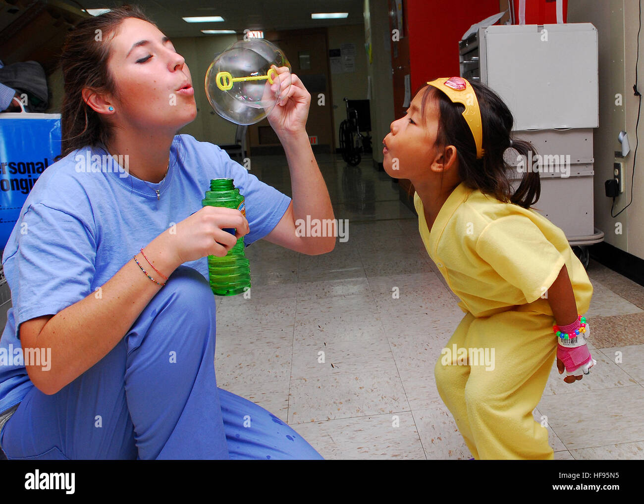 Kayla Hamrick, left, a member of Latter-day Saint Charities, blows bubbles for a child in the pediatric ward of Military Sealift Command hospital ship USNS Mercy (T-AH 19), in Sihanoukville, Cambodia, June 22, 2010. Mercy traveled to Cambodia as the lead vessel for Pacific Partnership 2010, the fifth in a series of annual U.S. Pacific Fleet humanitarian and civic assistance endeavors aimed at strengthening regional partnerships. (U.S. Navy photo by Mass Communication Specialist 2nd Class Eddie Harrison/Released) 100622-N-4044H-013 (4729963833) Stock Photo