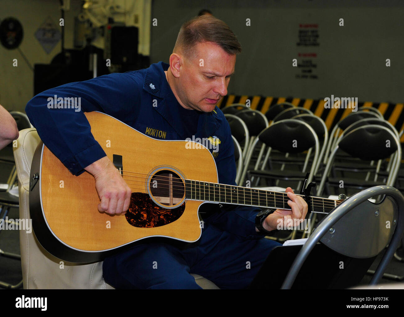 Cmdr. Joel Morton, a Navy Chaplain, plays guitar during Christmas caroling aboard the amphibious assault ship USS Boxer (LHD 4). Boxer is the flagship for the Boxer Amphibious Ready Group and, with the embarked 13th Marine Expeditionary Unit, is deployed in support of maritime security operations and theater security cooperation efforts in the U.S. 5th Fleet area of responsibility. (U.S. Navy Photo by Mass Communication Specialist 3rd Class Mayra A. Knight/Released) Christmas caroling 131225-N-PZ713-108 Stock Photo