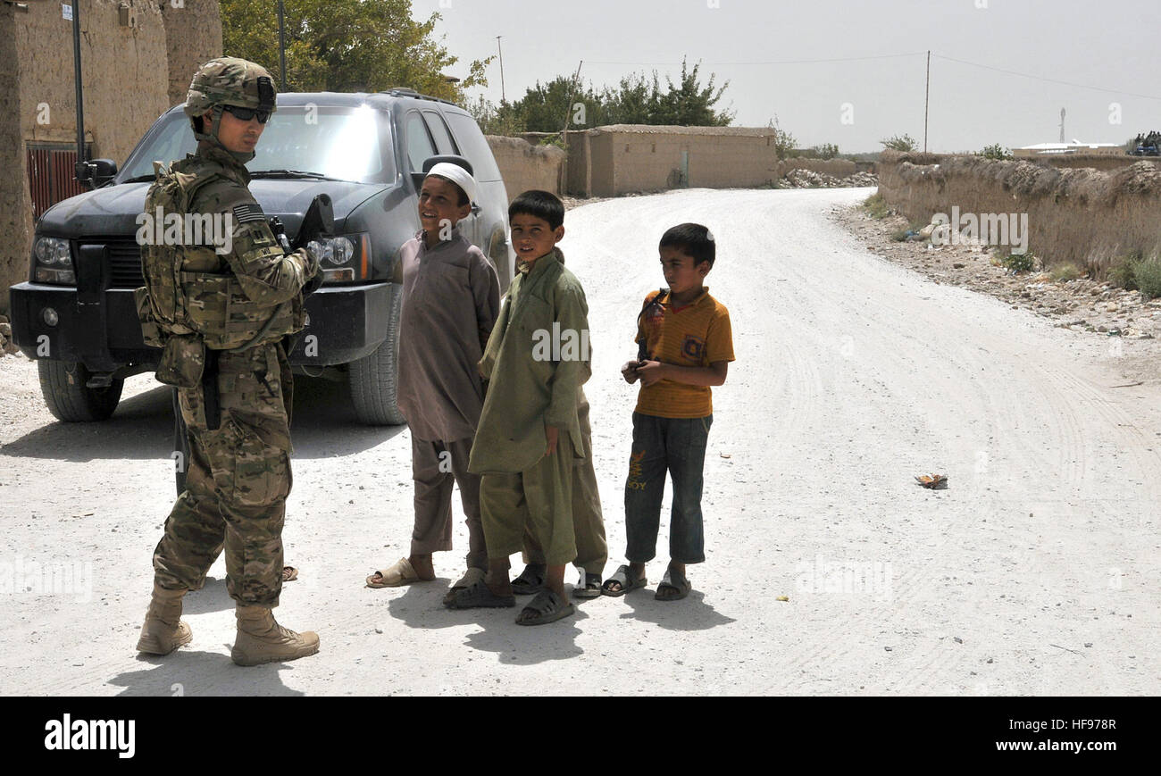 SEH DU-KAHN, Afghanistan (Aug. 10, 2011) -- Curious Afghan boys from the village of Seh Du-kahn look at U.S. Army Capt. Timothy Wu, a native of McLean, Va., and a Corps of Engineers officer from the 62nd Engineer Battalion, 36th Engineer Bridgade at Fort Hood, Texas, and currently assigned to Combined Joint Interagency Task Force 435, as he stands guard while other engineers from CJIATF 435 conduct a survey of the utilities available to the village.  CJIATF 435 engineers conducted site surveys of the region as part of a project to connect the Justice Center in Parwan to Afghanistan's national  Stock Photo