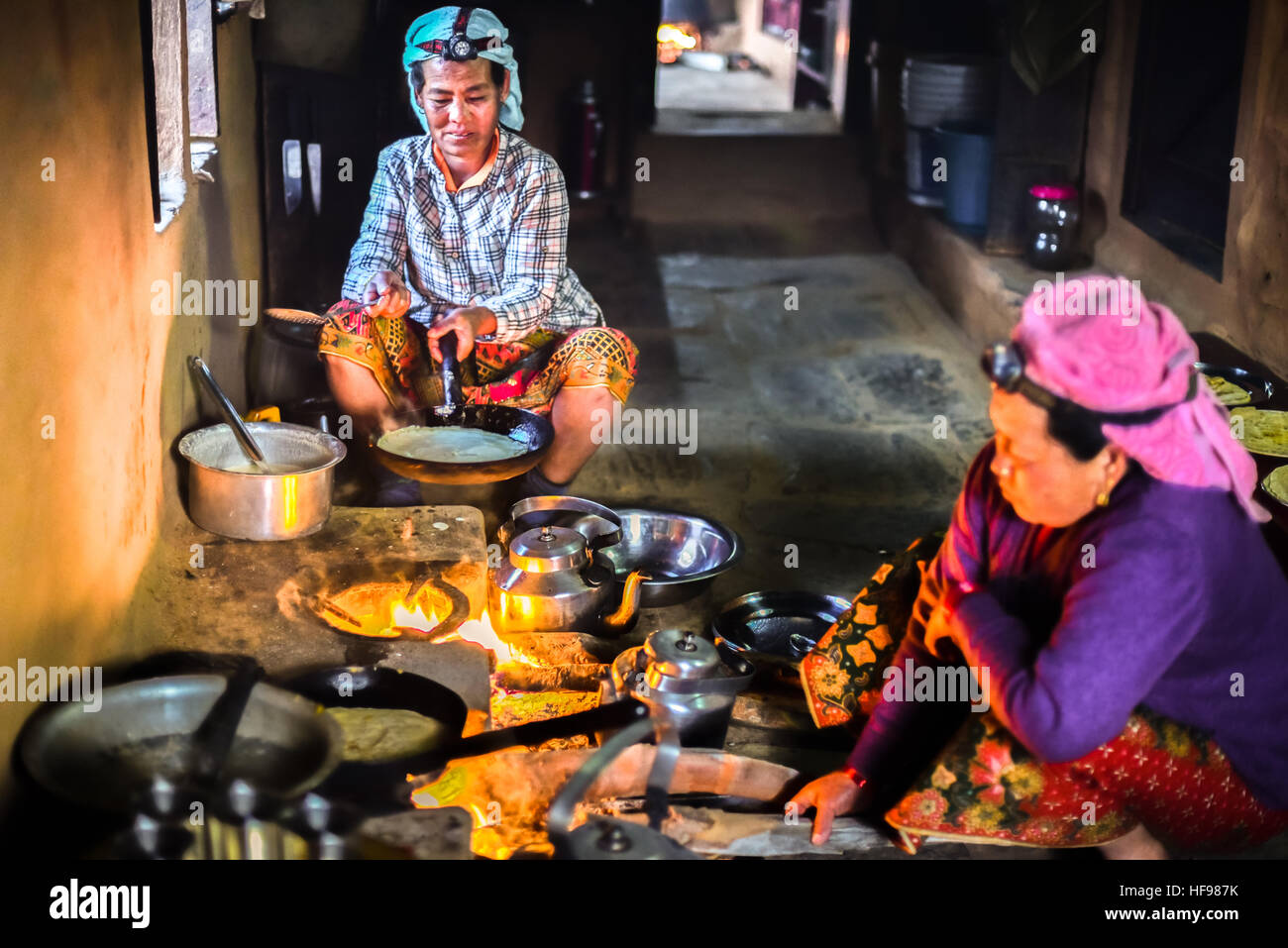 Two Nepali women making pancakes in the kitchen. Panchase region, Kaski district, Nepal. Stock Photo